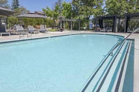 a swimming pool with chairs and umbrellas next to a resort style pool
