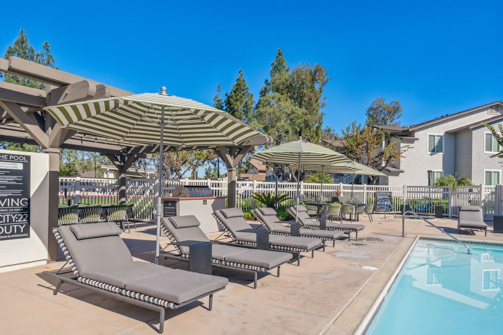 a pool with lounge chairs and umbrellas next to a building