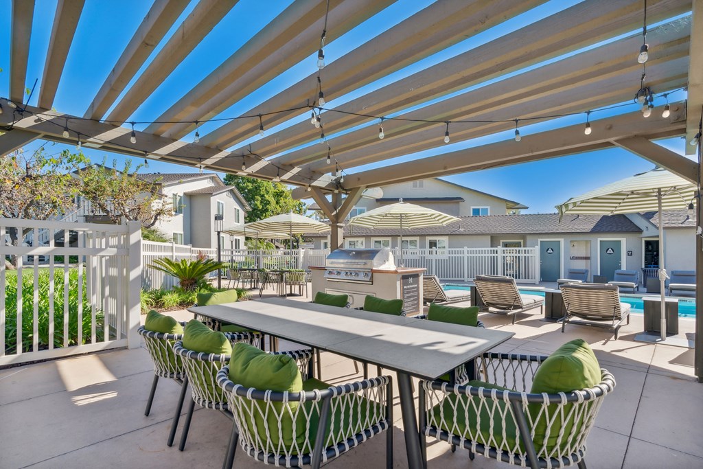 a patio with a dining table and chairs and a pool