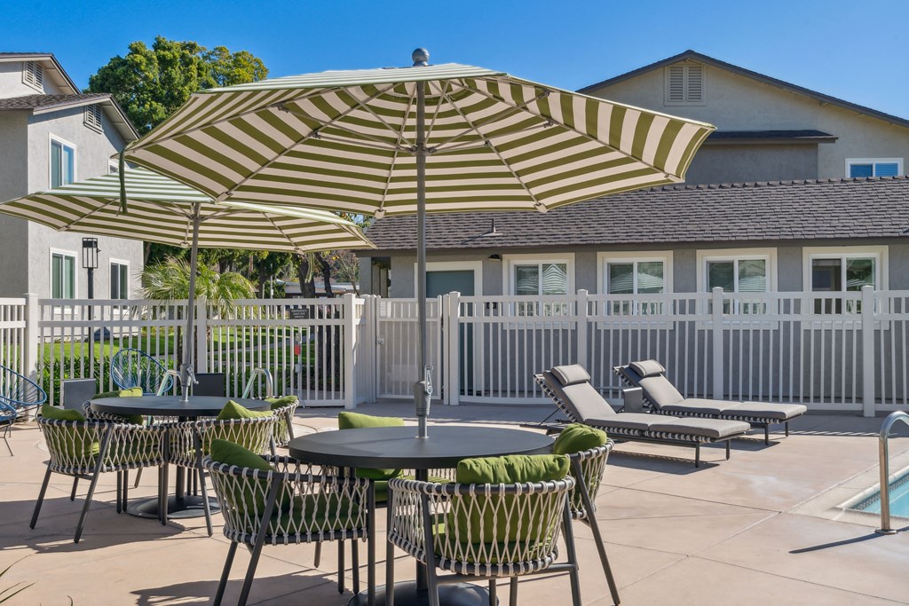a patio with tables and chairs and umbrellas in front of a house