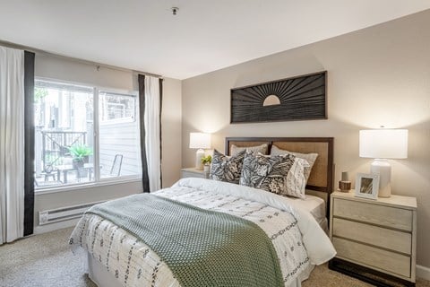 A bedroom with a large bed and a balcony with a table and chairs.