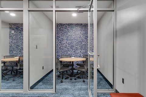 a small meeting room with glass walls and a blue tiled wall in the background