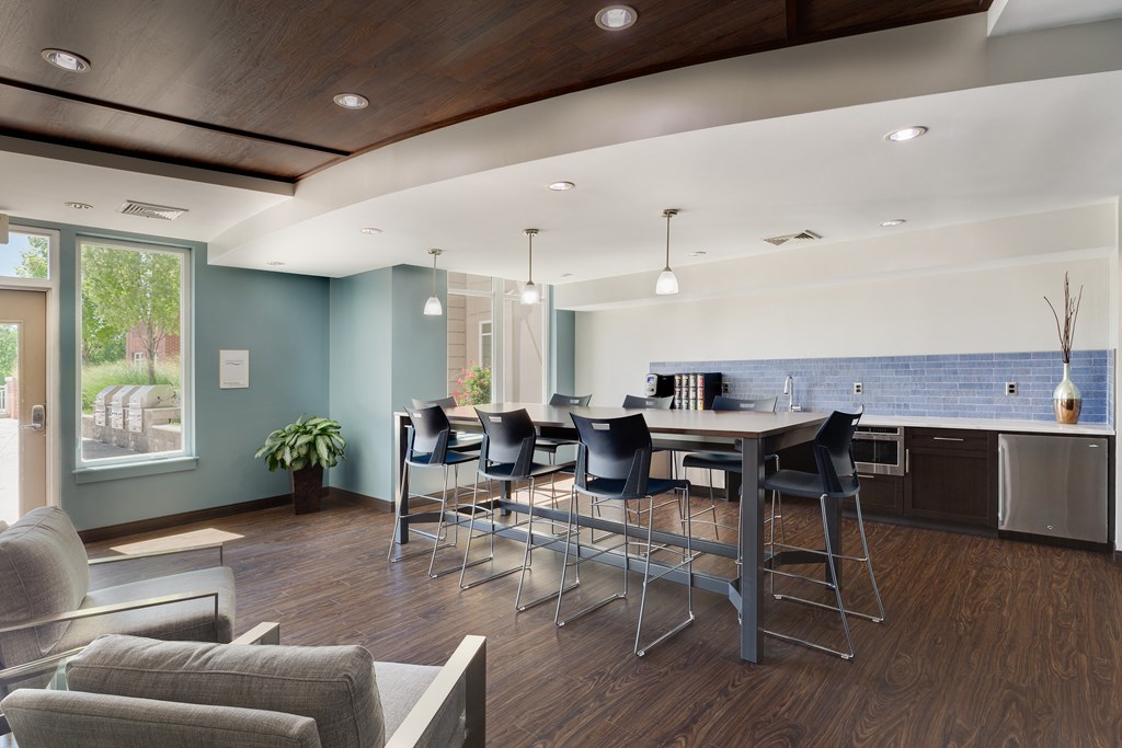 a room with a large table and chairs and a kitchen in the background