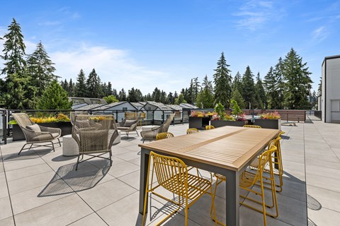 A patio with a table and chairs is surrounded by trees.