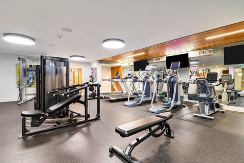 A gym with a variety of equipment including treadmills, weights, and exercise machines.
