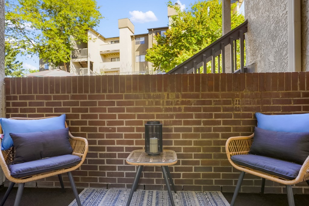 a patio with two chairs and a table and a brick wall