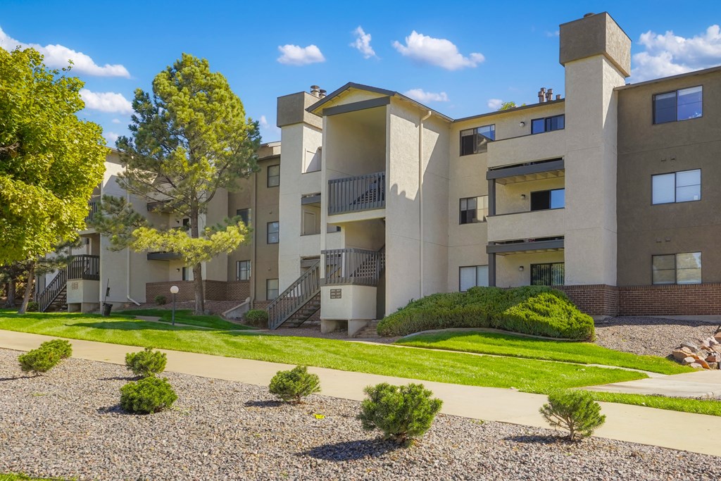 an exterior view of an apartment building with a sidewalk and grass