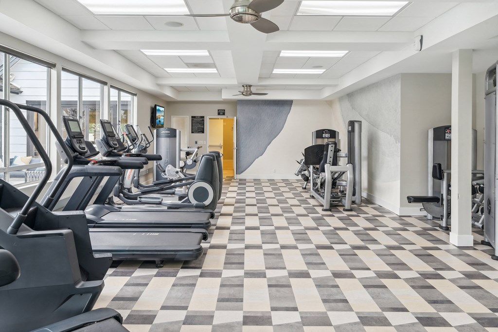 a gym with cardio machines and a checkered floor