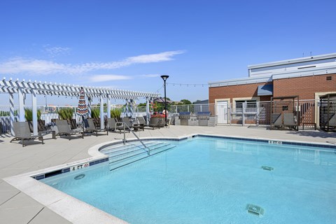a swimming pool with chairs around it and a building in the background
