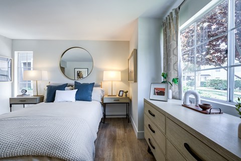 a bedroom with a bed and a dresser in front of a window