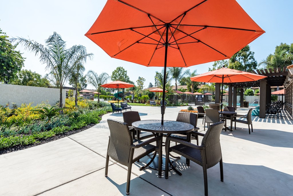 a patio with a table and chairs and orange umbrellas
