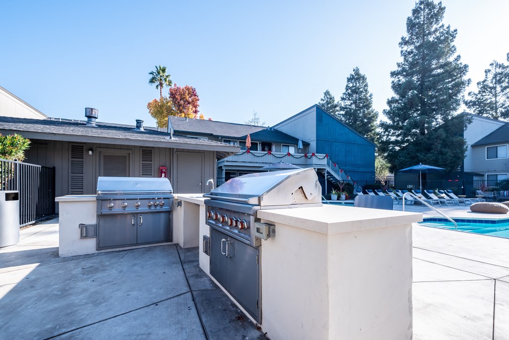 an outdoor kitchen and pool area at the enclave at woodbridge apartments in sugar land, tx