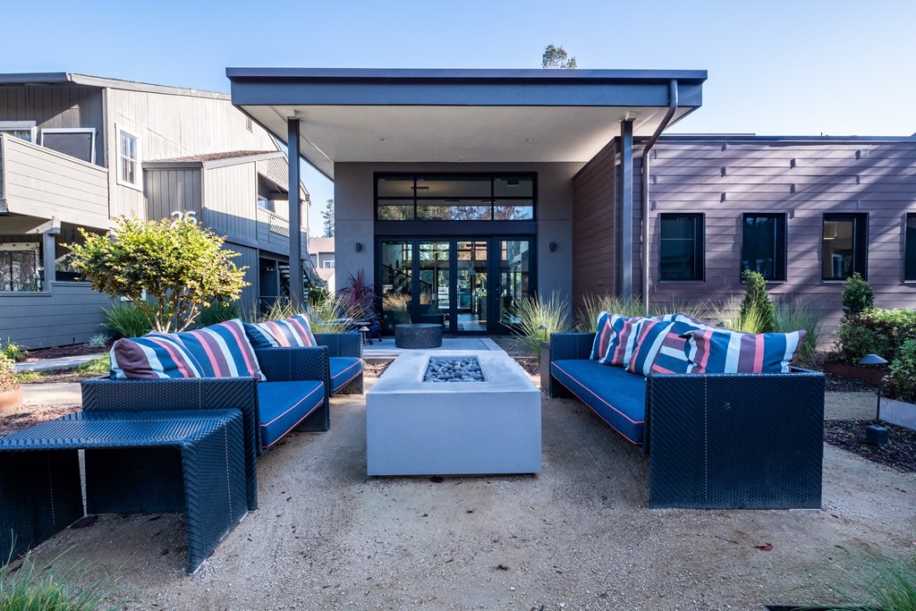 a patio with blue couches and a white firepit