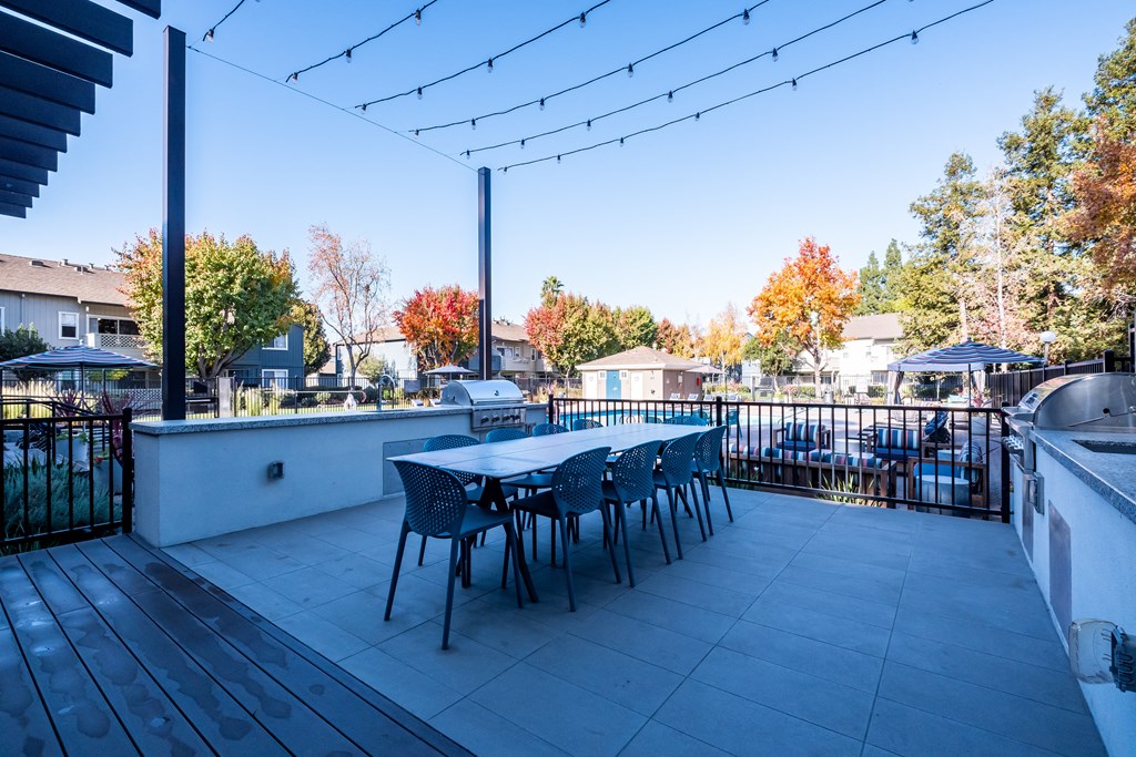 a patio with a table and chairs and a grill