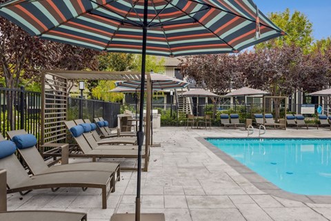 A pool area with sun loungers and umbrellas.