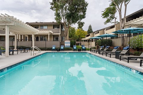 A large swimming pool with a sun lounger and umbrella.