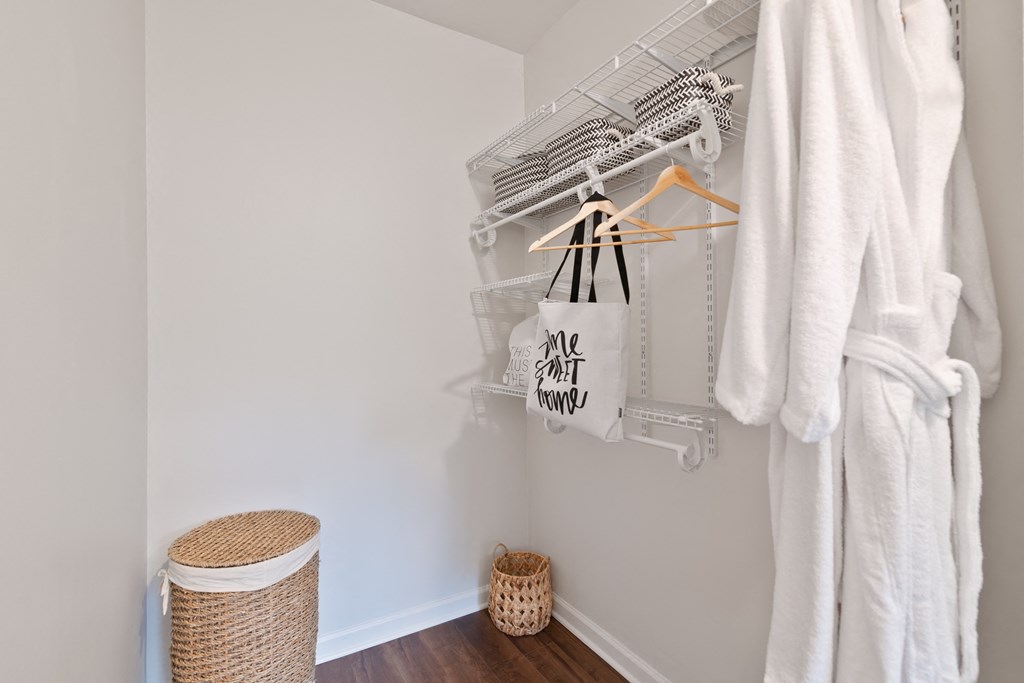 a small bathroom with a basket and a rack with towels and a tote bag