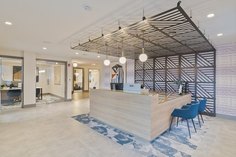 a reception area with a wooden reception desk and blue chairs
