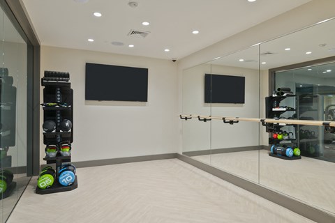 a workout room with a mirrored wall and a rack of dumbbells