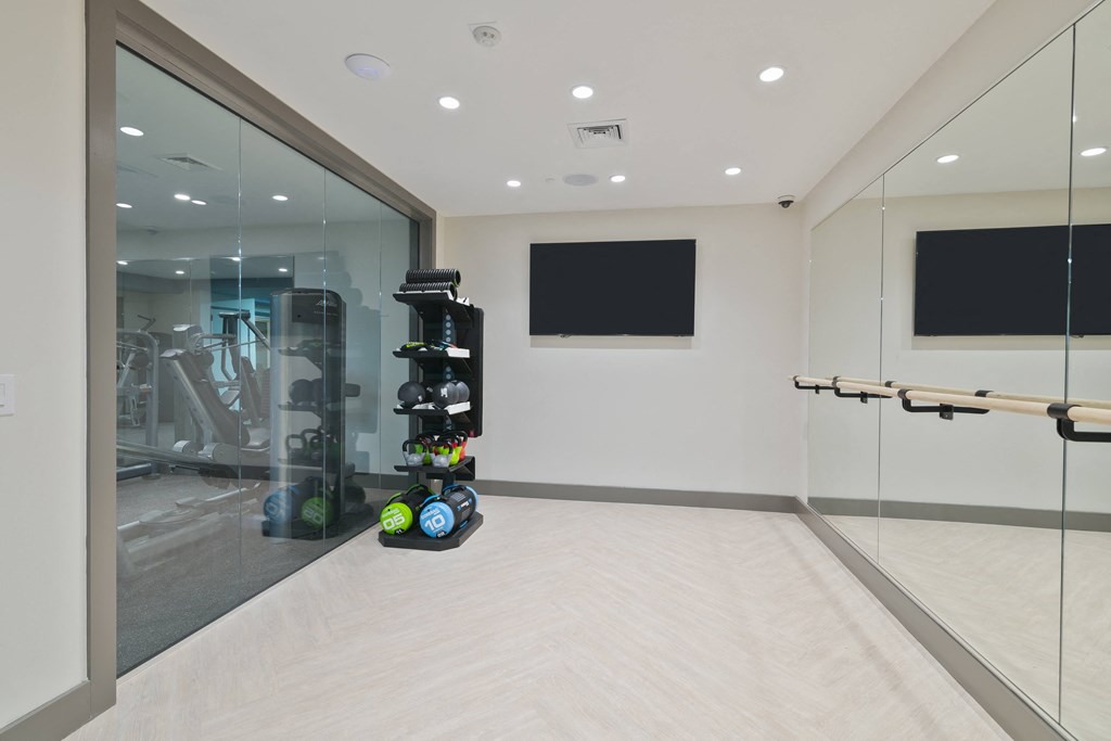 a fitness room with a treadmill and a tv on the wall
