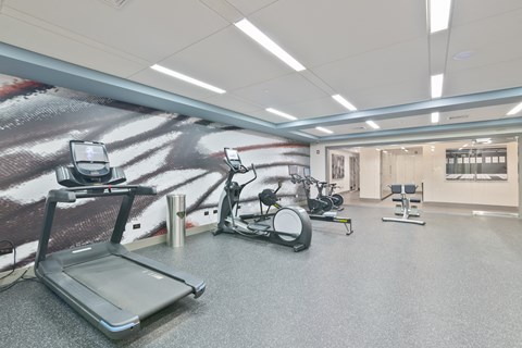 a gym with exercise equipment and a wall mural of a soccer field
