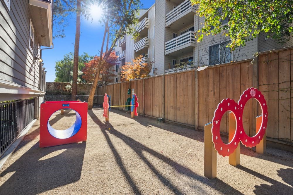 A playground with a red tunnel and two red rings.