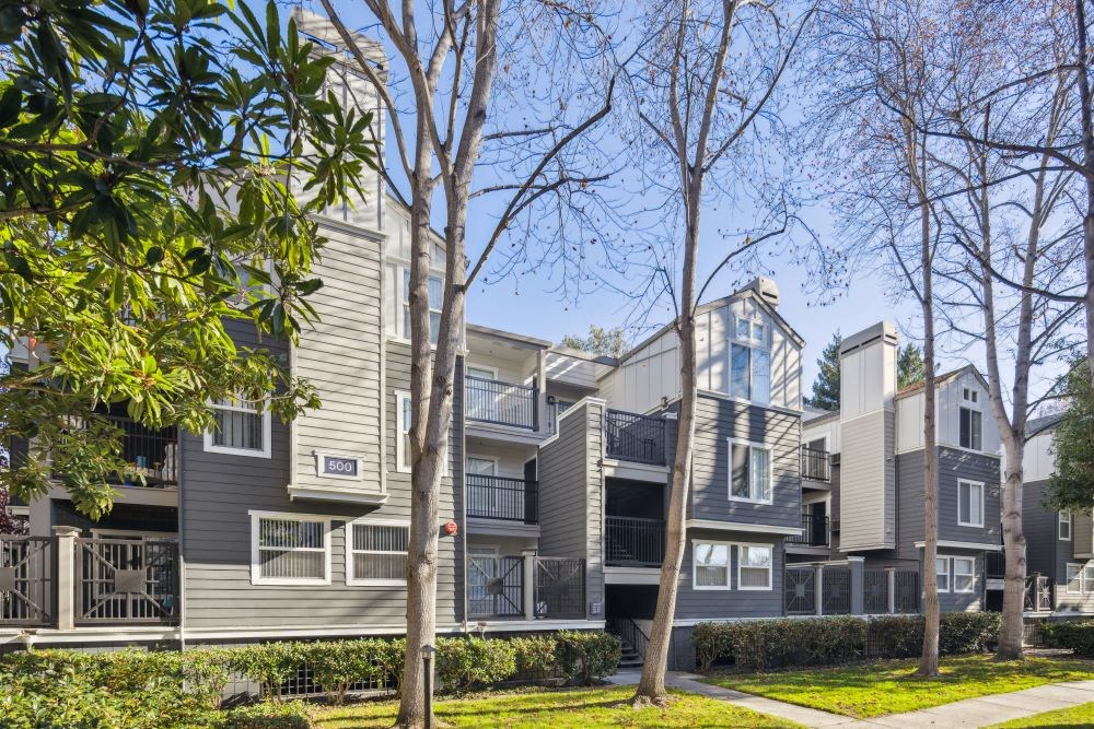 A modern apartment complex with balconies and trees in front.