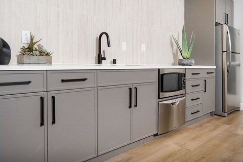 A kitchen with grey cabinets and a wooden floor.