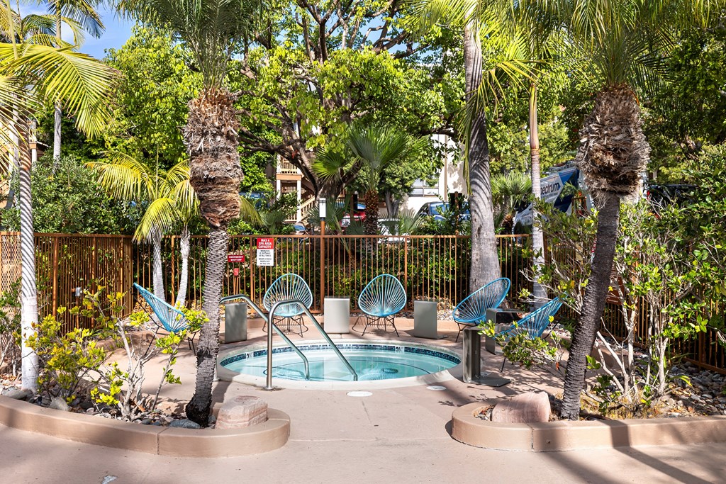 a small pool with blue chairs and palm trees