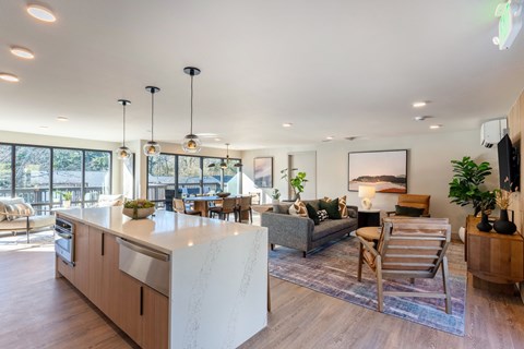 A modern kitchen with a large island and a living area with a couch and chairs.
