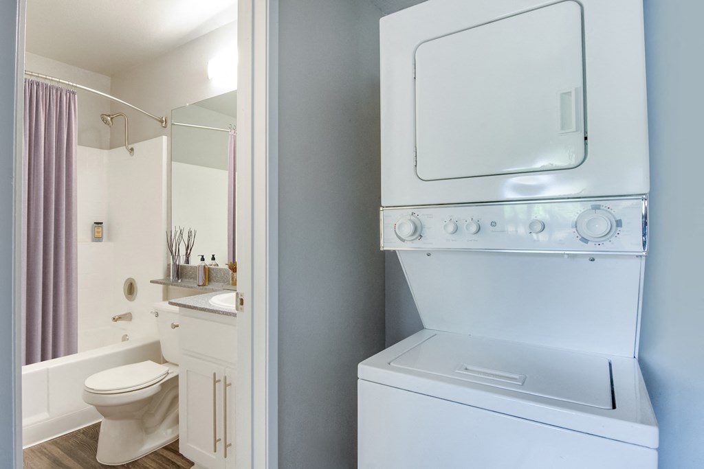 a white washer and dryer in a bathroom with a toilet and a sink