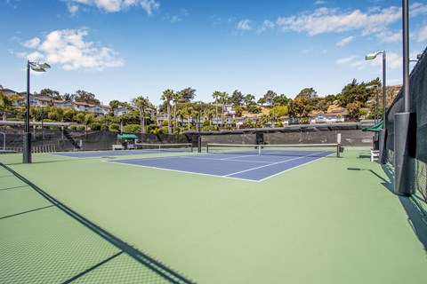 A tennis court with a blue and green surface and a fence surrounding it.