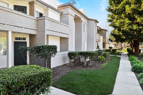 A row of houses with green lawns and trees.