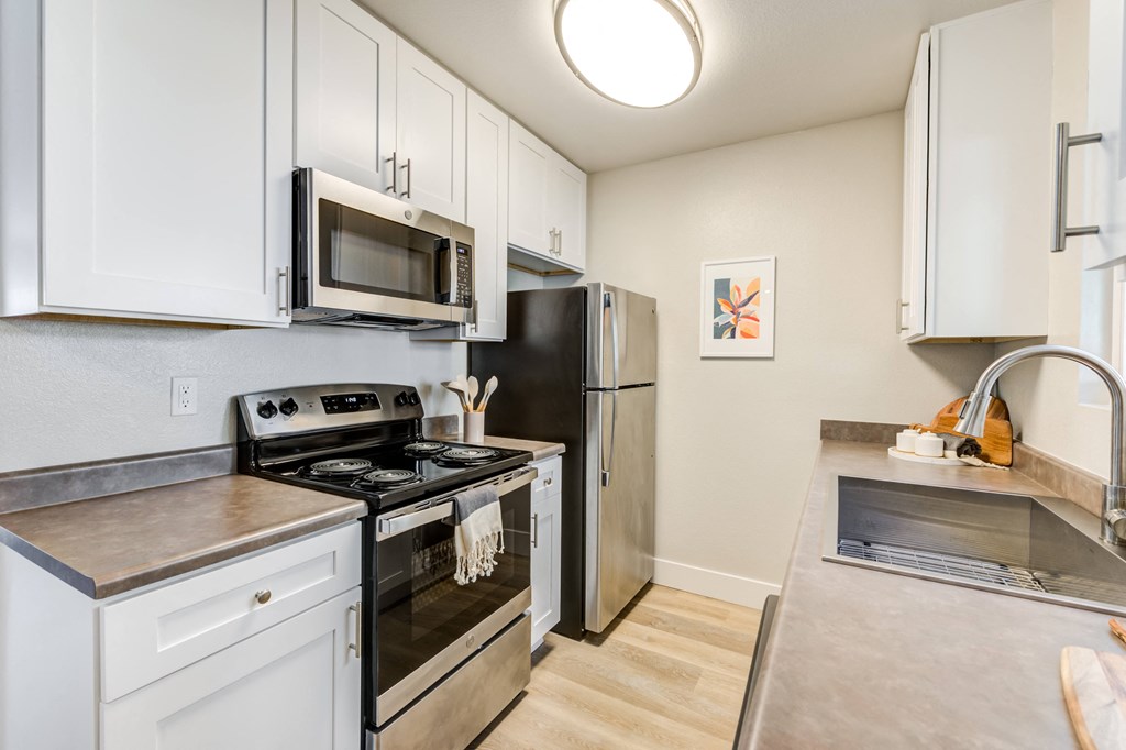 a kitchen with white cabinets and stainless steel appliances and a refrigerator
