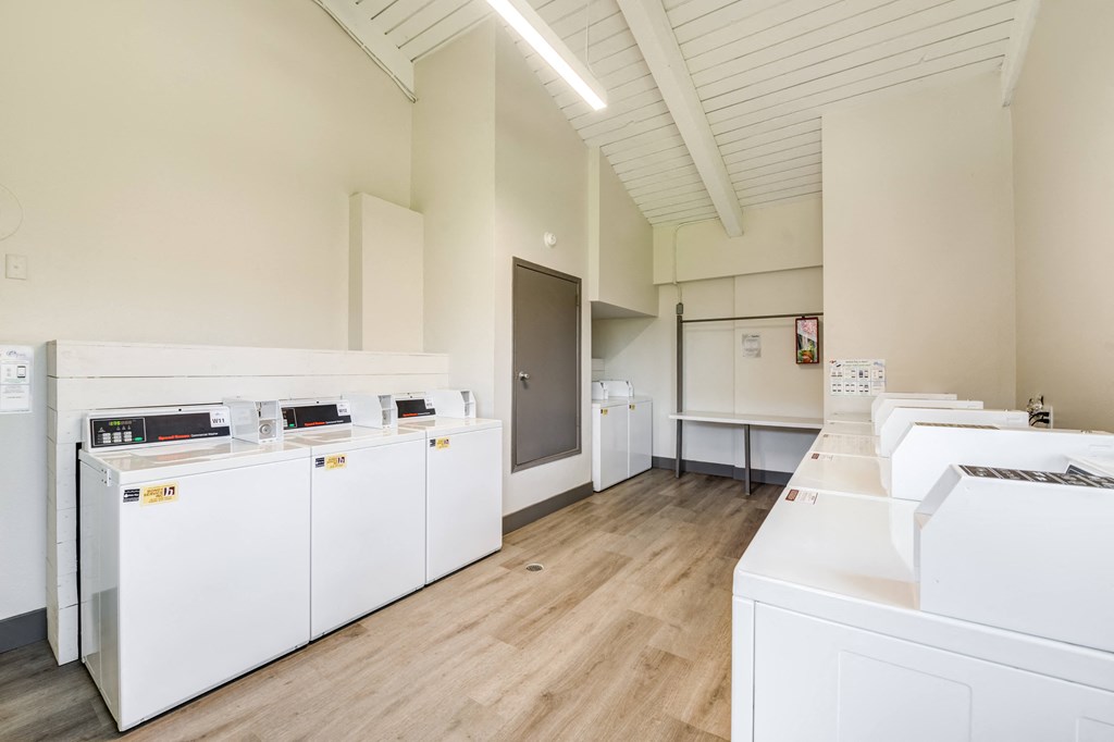 a community room with white appliances and a wood floor