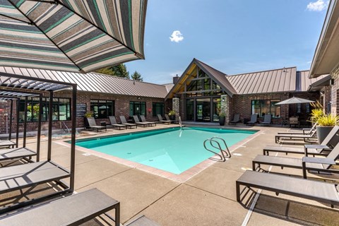 A pool area with sun loungers and a striped umbrella.