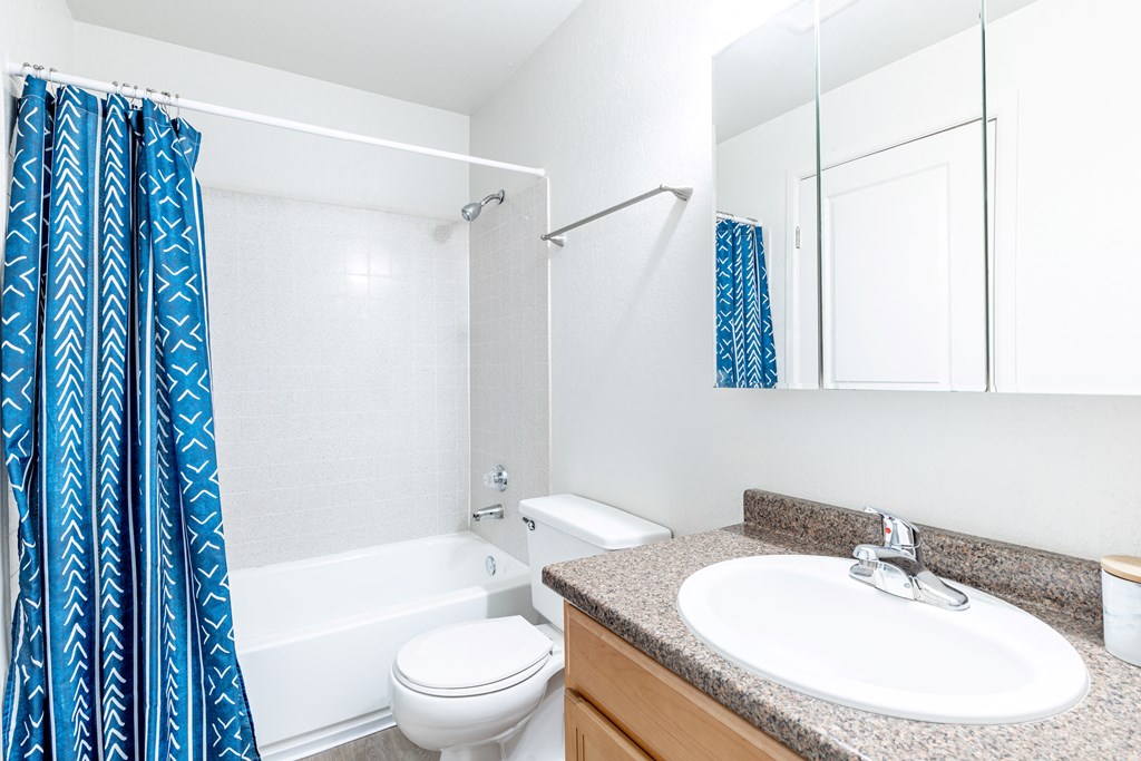 a bathroom with white fixtures and a blue shower curtain