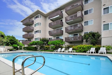 A swimming pool in front of a large apartment building.