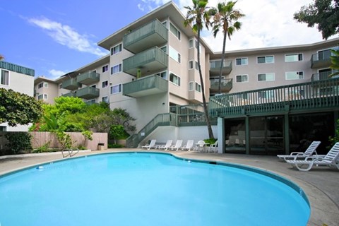 A swimming pool in front of a building with a balcony.
