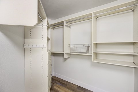 a walk in closet with white walls and shelves and