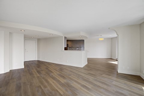 a living room and kitchen with white walls and wood flooring