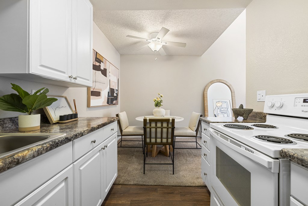 a kitchen with white appliances and a dining room with a table and chairs