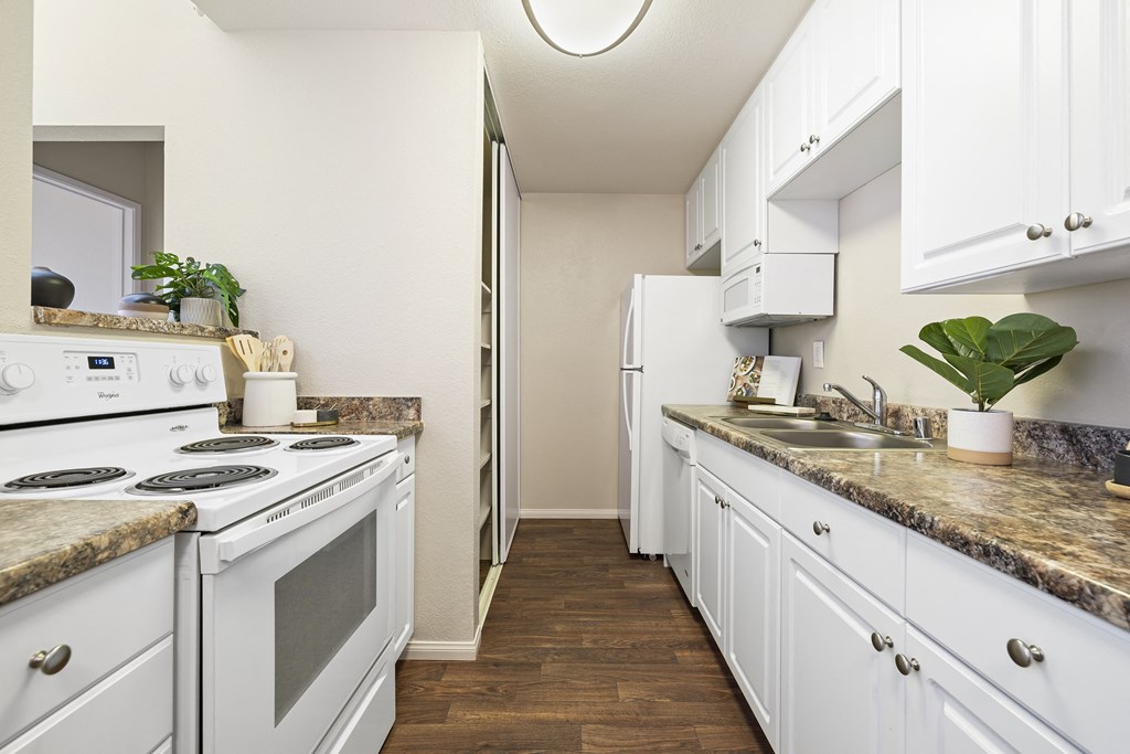 a spacious kitchen with white appliances and white cabinets