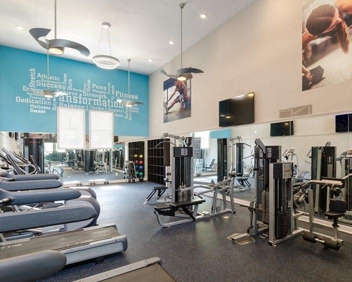 a gym with a lot of weights and a tv