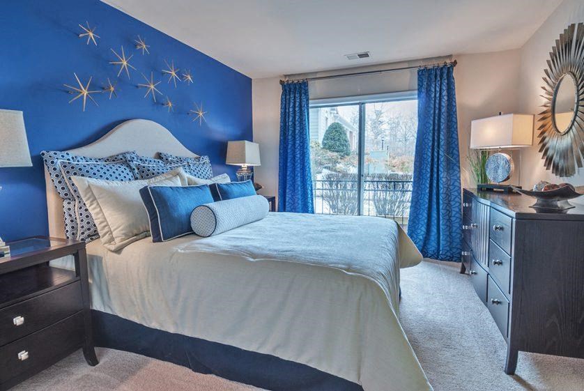 a blue and white bedroom with a bed and a window