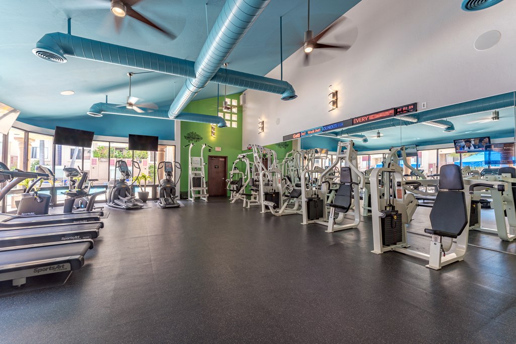 a large fitness room with cardio machines and other exercise equipment