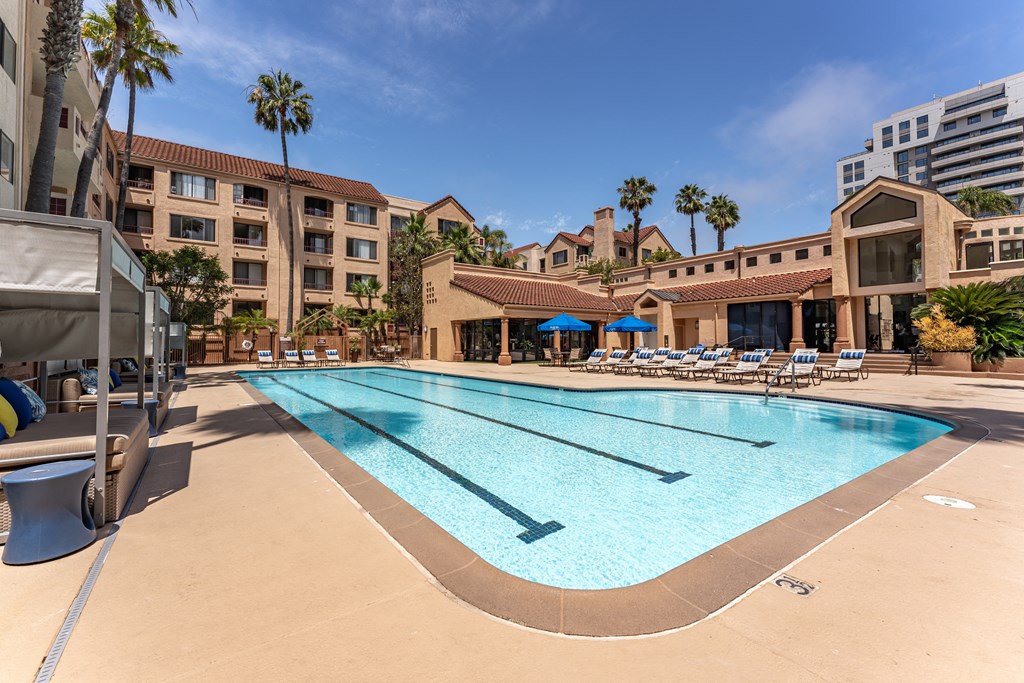 a swimming pool with lounge chairs and umbrellas in front of a hotel