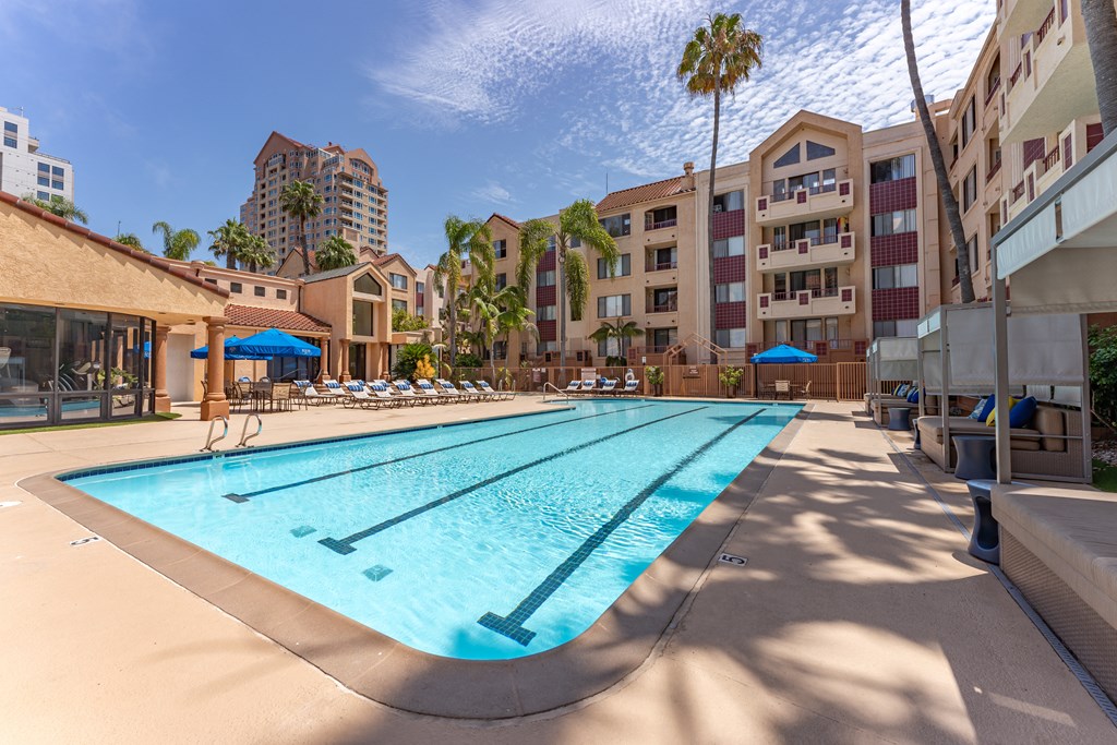 a swimming pool with lounge chairs and umbrellas in front of a hotel
