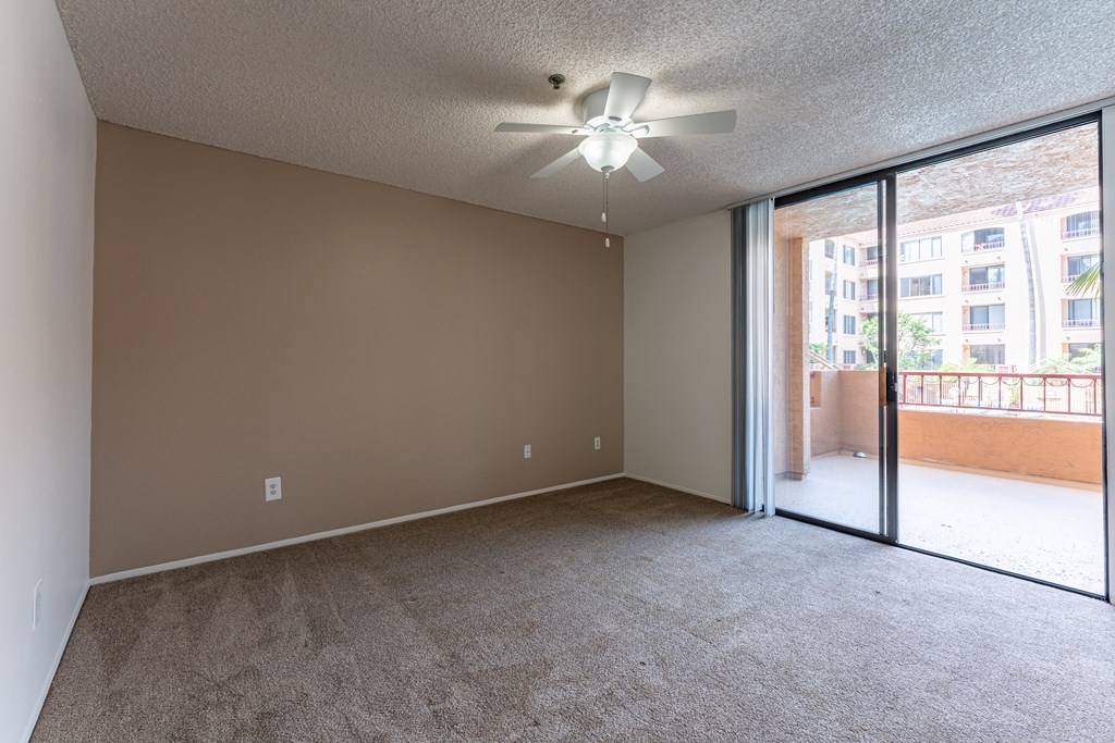 a bedroom with a ceiling fan and a sliding glass door to a balcony