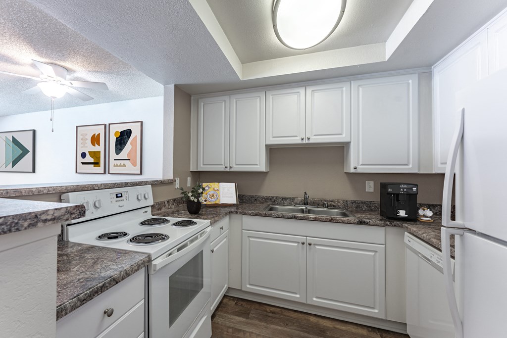 a kitchen with white cabinets and white appliances and granite counter tops